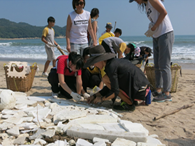 一班学生正在海滩收集塑胶垃圾来创作艺术品