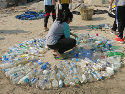 一班学生正在海滩收集塑胶垃圾来创作艺术品